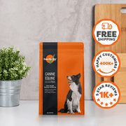 Orange and black package of Rose Hip Vita with a dog on it, next to a plant and cutting board.
